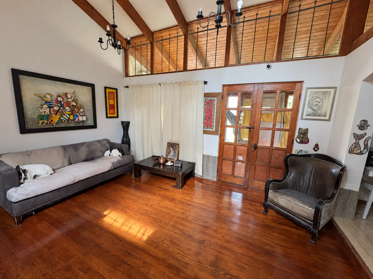 Interior de la casa con piso de madera, sillones y un perro descansando